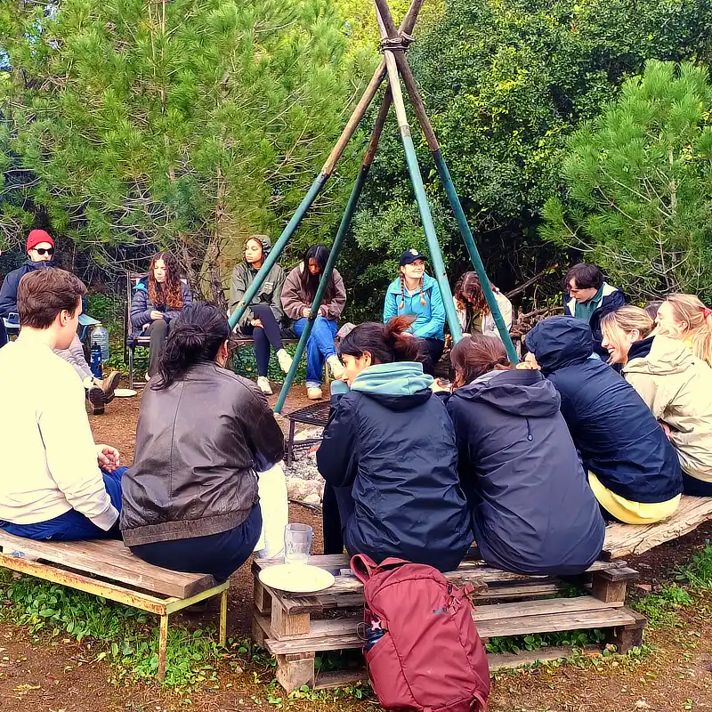 Grupo de participantes reunido em redor de uma fogueira durante uma atividade da Arrábida Walks and Crafts